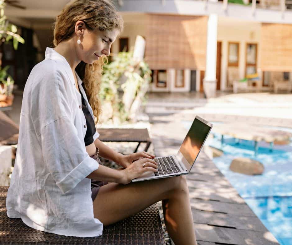 student applying for scholarships by the pool on summer break
