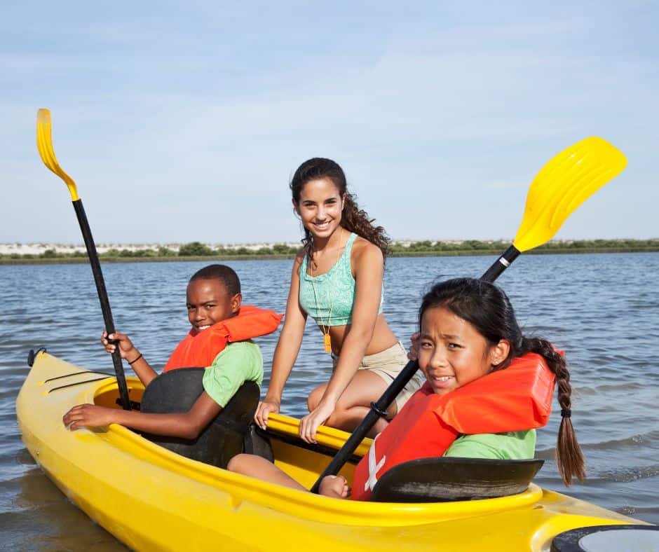 camp counselor teaching kayaking to kids as a summer job for teens