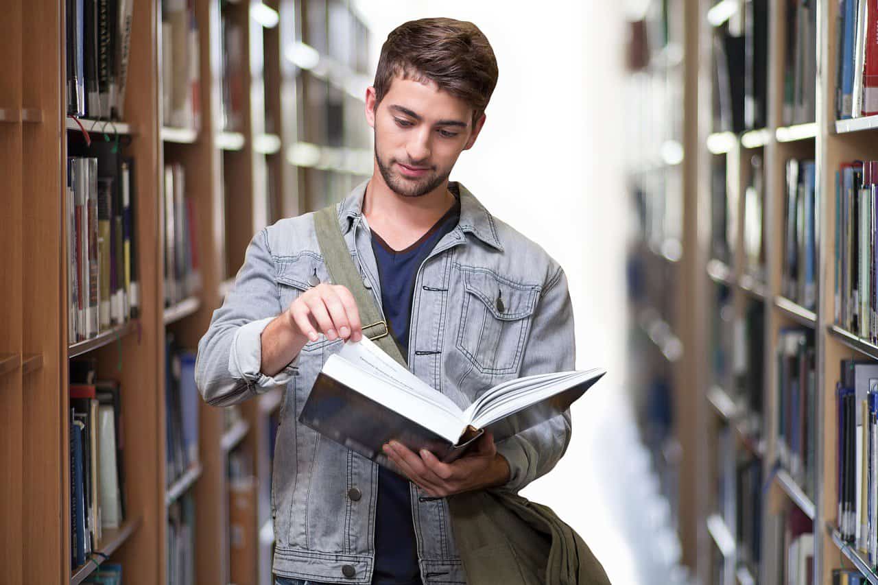 male in library looking through books